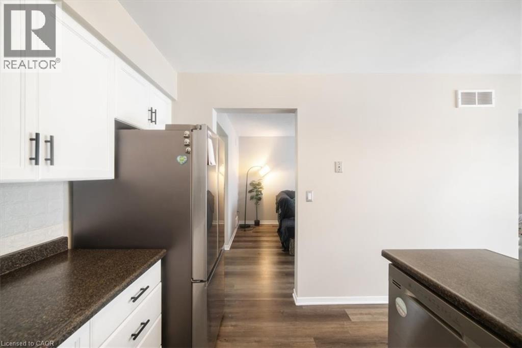 Kitchen featuring stainless steel appliances, dark wood finished floors, white cabinets, and decorative backsplash - 25 Meadowvale Drive Unit# 3, Fonthill, ON - Indoor Photo Showing Kitchen
