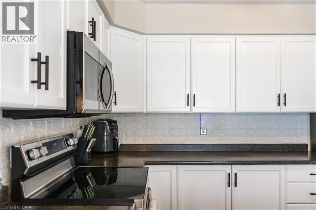 Kitchen with appliances with stainless steel finishes, white cabinetry, and backsplash - 25 Meadowvale Drive Unit# 3, Fonthill, ON - Indoor Photo Showing Kitchen