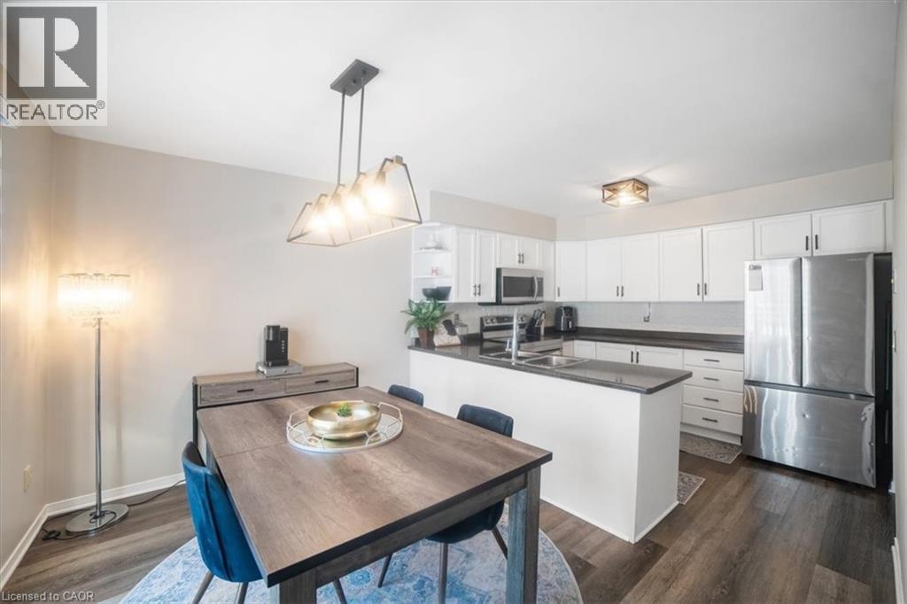 Kitchen with appliances with stainless steel finishes, white cabinetry, a peninsula, open shelves, and dark wood-type flooring - 25 Meadowvale Drive Unit# 3, Fonthill, ON - Indoor