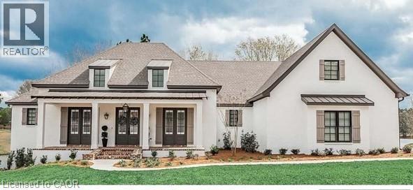 View of front facade with covered porch, a front lawn, a standing seam roof, stucco siding, and a metal roof - 16 Abingdon Road Unit# 8, Caistor Centre, ON - Outdoor With Facade