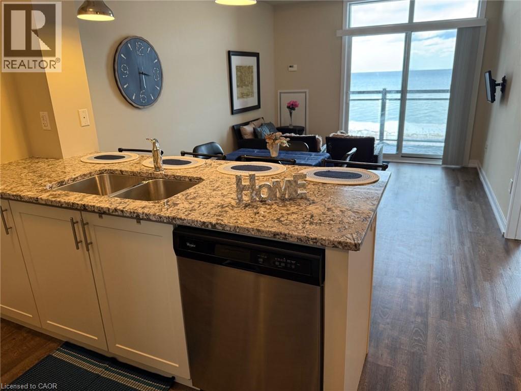 Kitchen featuring dishwasher, light stone counters, open floor plan, and dark wood-style floors - 35 Southshore Crescent Unit# 303, Stoney Creek, ON - Indoor Photo Showing Kitchen With Double Sink