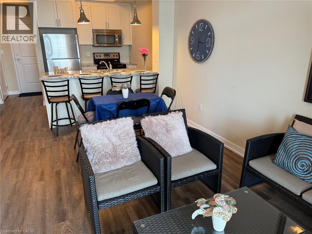 Living room featuring dark wood-style flooring and baseboards - 35 Southshore Crescent Unit# 303, Stoney Creek, ON - Indoor