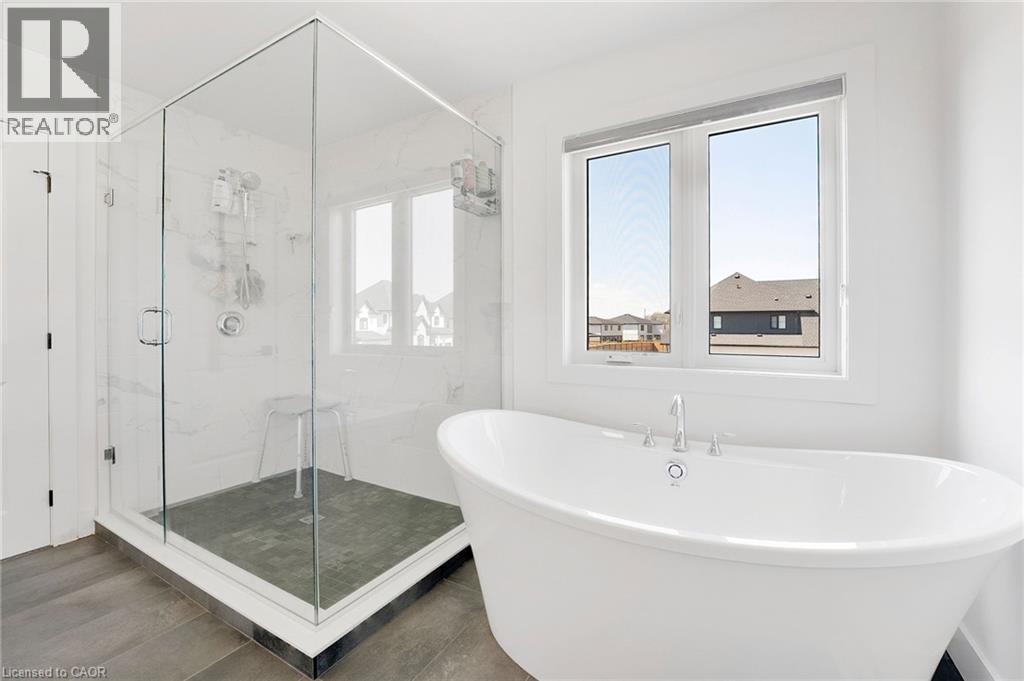 Bathroom with a marble finish shower, a freestanding tub, and dark wood-style floors - 7266 Silver Creek Circle, London, ON - Indoor Photo Showing Bathroom