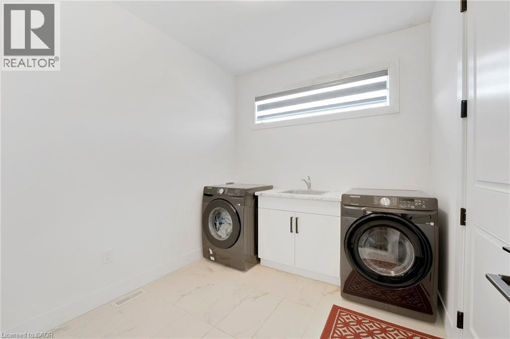 Laundry area with cabinet space, light marble finish floors, and separate washer and dryer - 7266 Silver Creek Circle, London, ON - Indoor Photo Showing Laundry Room
