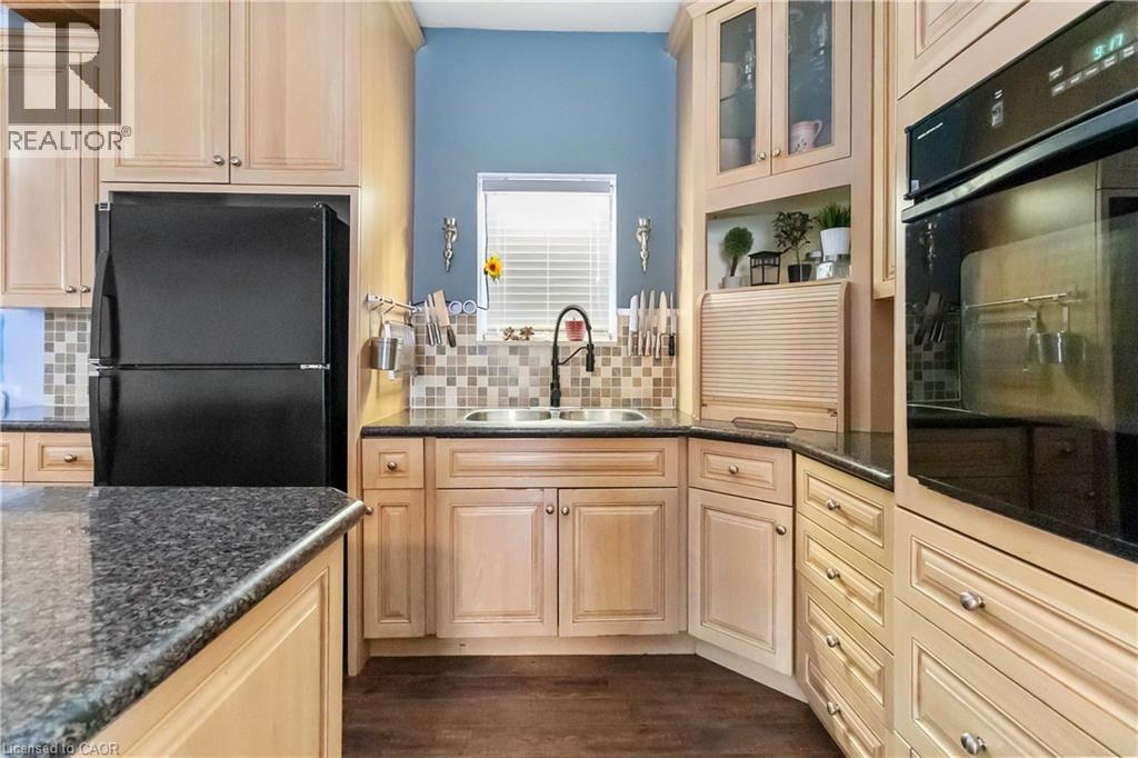 Kitchen featuring black appliances, glass insert cabinets, dark stone countertops, and decorative backsplash - 112 Eagle Avenue, Brantford, ON - Indoor Photo Showing Kitchen With Double Sink