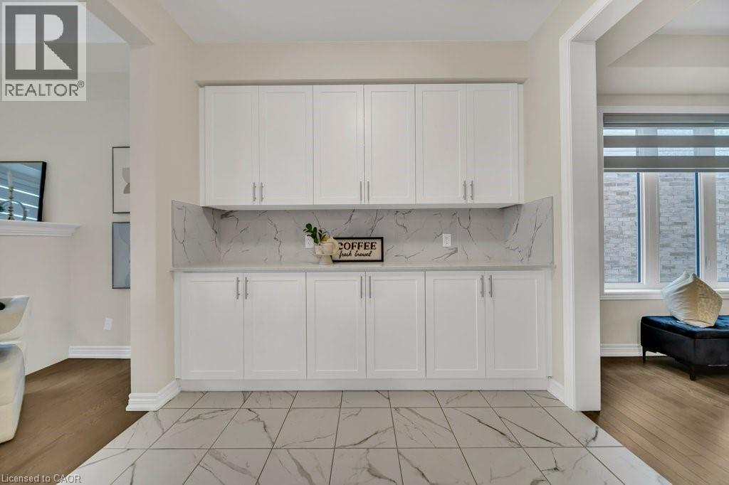 Kitchen with white cabinetry, decorative backsplash, light stone countertops, and light wood-style flooring - 285 Broadacre Drive, Kitchener, ON - Indoor