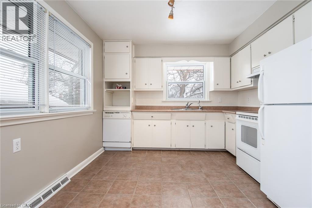 Kitchen with white appliances, decorative backsplash, open shelves, white cabinets, and light tile patterned floors - 120 Fourth Avenue, Kitchener, ON - Indoor Photo Showing Kitchen