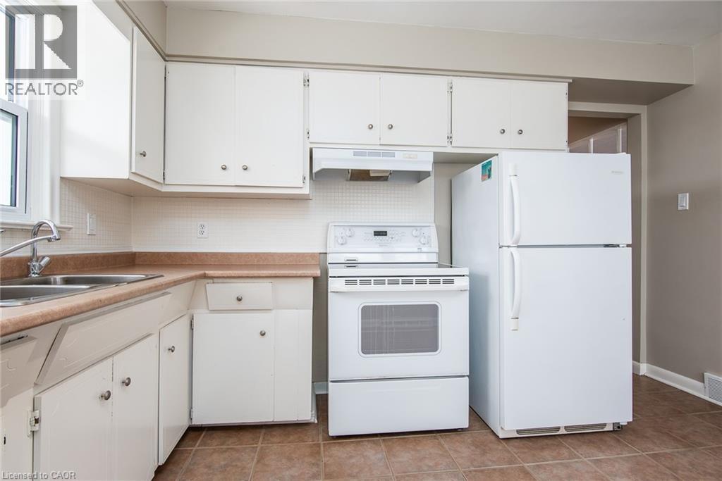 Kitchen featuring white appliances, white cabinetry, decorative backsplash, and under cabinet range hood - 120 Fourth Avenue, Kitchener, ON - Indoor Photo Showing Kitchen With Double Sink