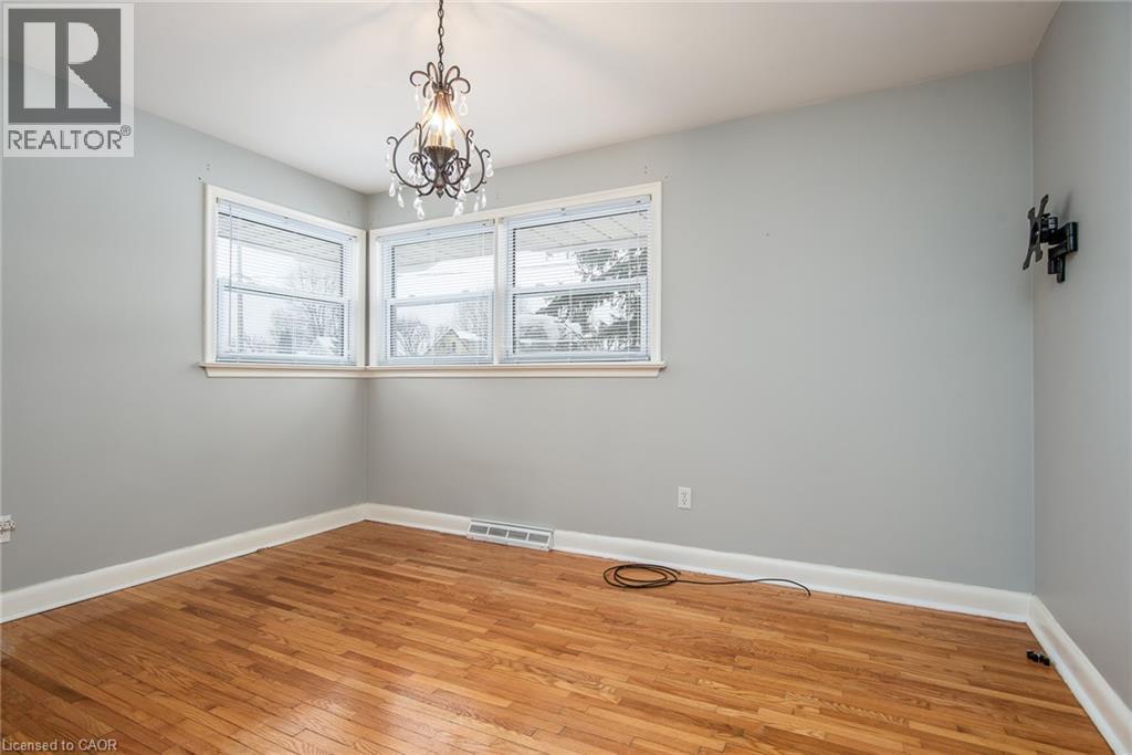 Empty room with light wood-style floors and a chandelier - 120 Fourth Avenue, Kitchener, ON - Indoor Photo Showing Other Room