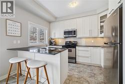 Kitchen with appliances with stainless steel finishes, a kitchen breakfast bar, white cabinetry, and backsplash -
