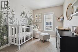 Carpeted bedroom with a crib and baseboards -