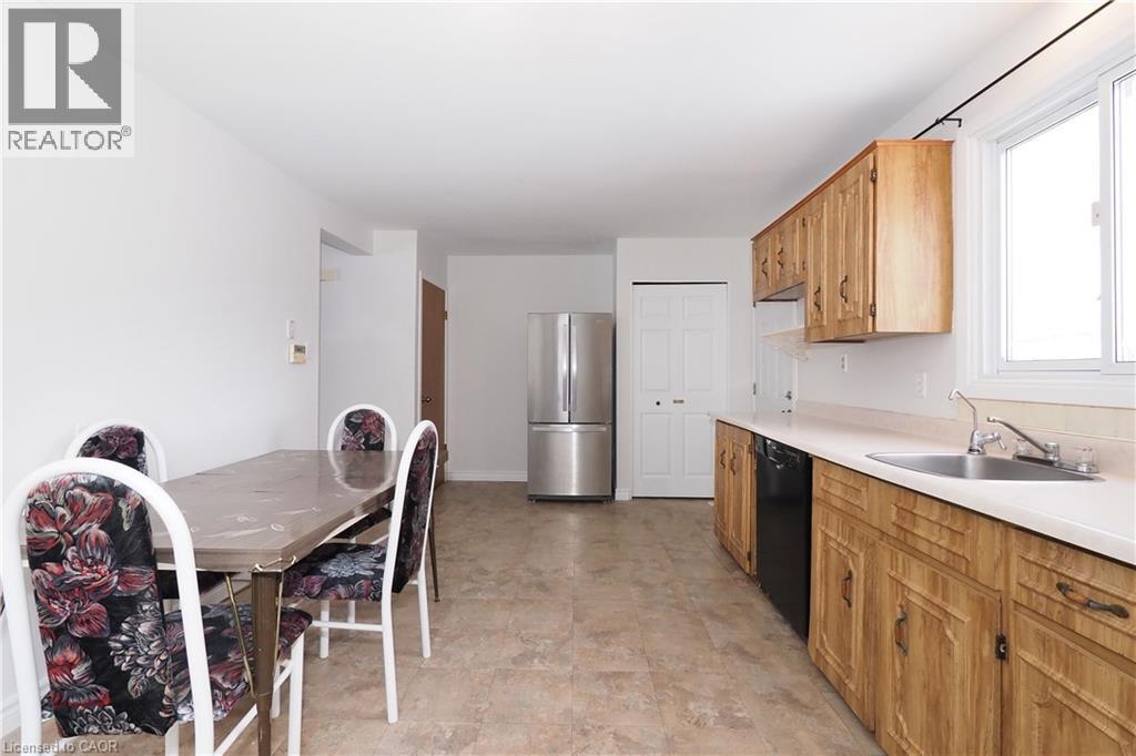Kitchen featuring light countertops, freestanding refrigerator, black dishwasher, and brown cabinets - 10 Balfour Crescent, Kitchener, ON - Indoor Photo Showing Kitchen