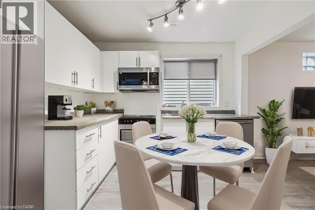 Kitchen with appliances with stainless steel finishes, white cabinetry, and light wood-style flooring - 28 Grove Street, Hamilton, ON - Indoor