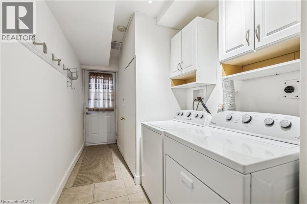 Laundry room with cabinet space, washer and clothes dryer, and light tile patterned floors - 28 Grove Street, Hamilton, ON - Indoor Photo Showing Laundry Room