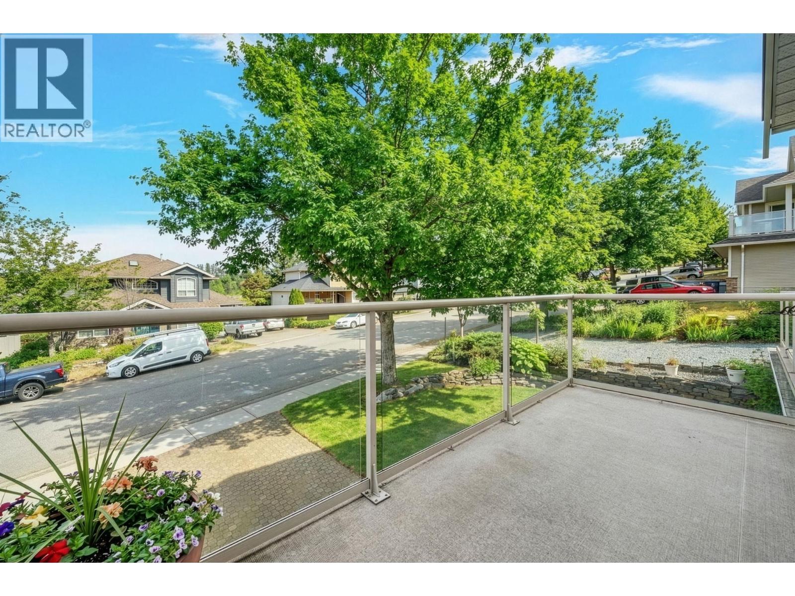 Balcony off of the primary bedroom overlooking the front yard. Exterior landscaping has been digitally enhanced to reflect summer conditions. Photos were taken during the winter season. - 867 Steele Road, Kelowna, BC - Outdoor