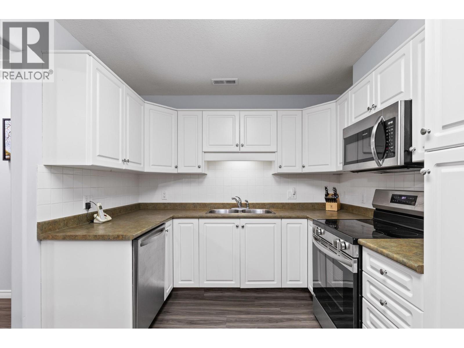 Walk-through Kitchen with stainless steel appliances - 1966 Durnin Road Unit# 105, Kelowna, BC - Indoor Photo Showing Kitchen With Double Sink