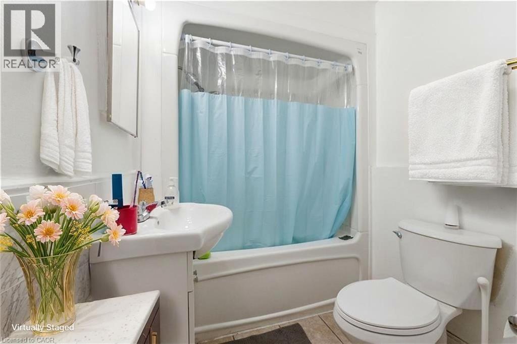 Full bath with vanity, shower / bathtub combination with curtain, and tile patterned floors - 180 Emerald Street S, Hamilton, ON - Indoor Photo Showing Bathroom