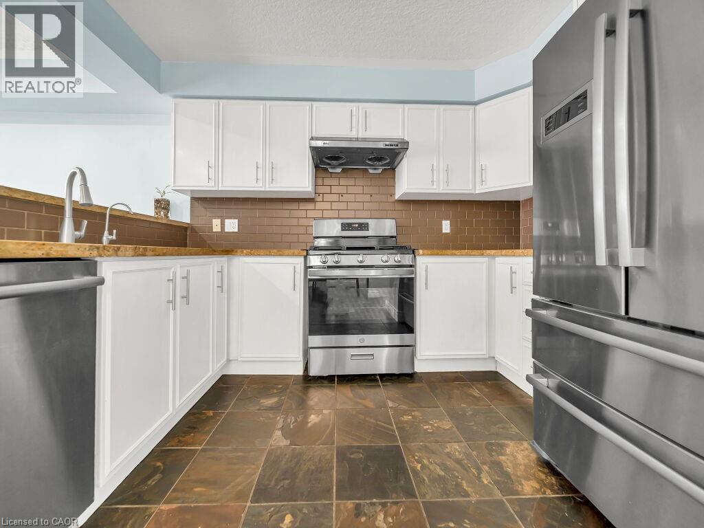 Kitchen with stainless steel appliances, white cabinets, tasteful backsplash, and a textured ceiling - 29 Amsterdam Crescent, Guelph, ON - Indoor Photo Showing Kitchen With Stainless Steel Kitchen