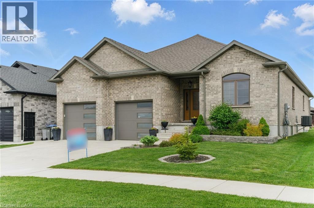 View of front facade featuring a front lawn, brick siding, concrete driveway, a garage, and a shingled roof - 107 Forbes Crescent, Listowel, ON - Outdoor With Facade