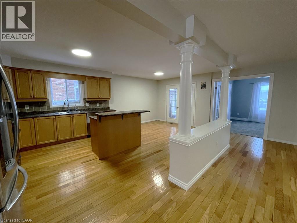 Kitchen featuring open floor plan, a breakfast bar area, stainless steel fridge with ice dispenser, decorative columns, and recessed lighting - 443 Lausanne Crescent, Waterloo, ON - Indoor