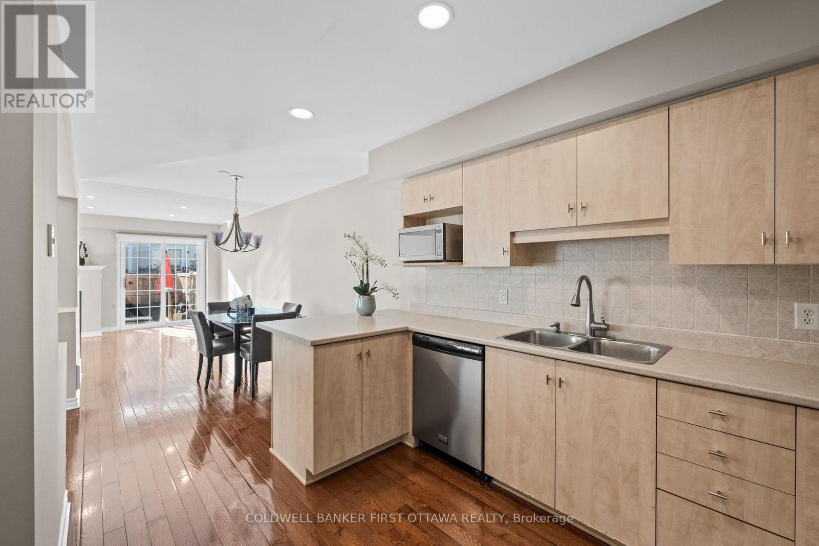 Tiled backsplash and breakfast bar seating. - 20 Fieldberry Private, Ottawa, ON - Indoor Photo Showing Kitchen With Double Sink