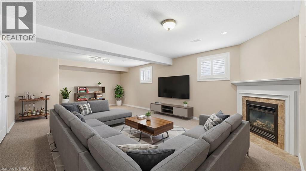 Carpeted family room with a tile fireplace, a textured ceiling, and beamed ceiling - 28 Mansfield Drive, St. George, ON - Indoor Photo Showing Living Room With Fireplace