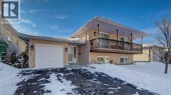 View of front of property featuring a garage, brick siding, and asphalt driveway -
