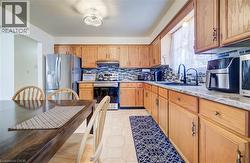 Kitchen with stainless steel appliances, under cabinet range hood, backsplash, and brown cabinets -