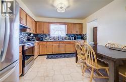 Kitchen featuring stainless steel appliances, brown cabinets, under cabinet range hood, and backsplash -