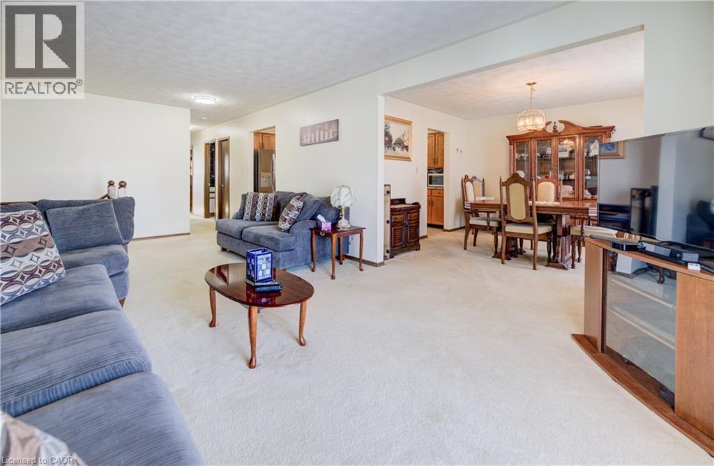 Living room featuring light colored carpet, a textured ceiling, and a chandelier - 42 Ruffian Road, Brantford, ON - Indoor Photo Showing Living Room