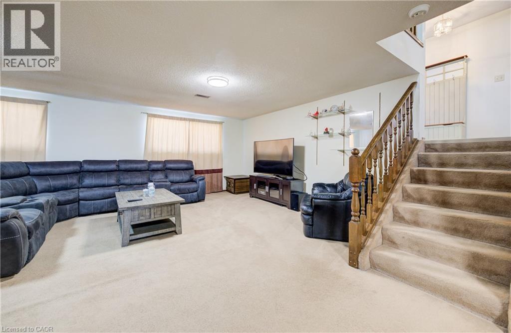Carpeted recreation room with a textured ceiling and stairs - 42 Ruffian Road, Brantford, ON - Indoor
