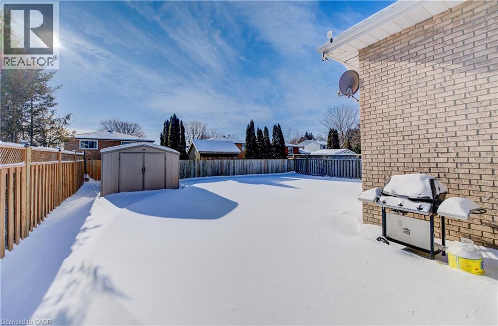 Yard covered in snow featuring a storage shed and a fenced backyard - 42 Ruffian Road, Brantford, ON - Outdoor