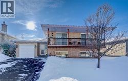View of front facade with brick siding, a balcony, a garage, and driveway -