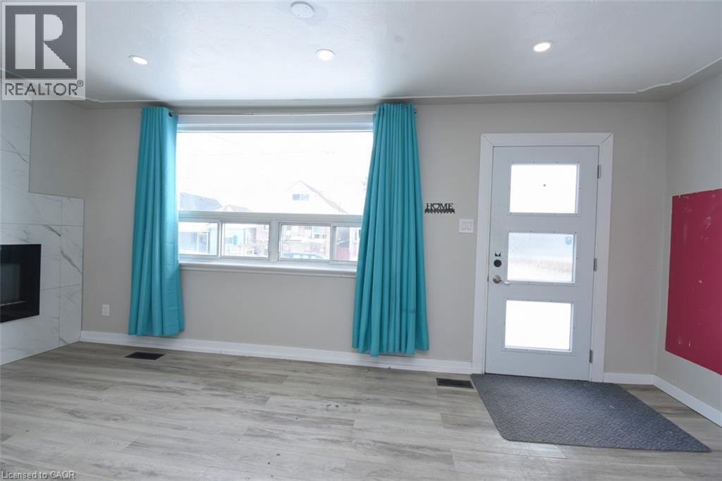 Foyer featuring light wood-style floors, a tiled fireplace, and recessed lighting - 371 Fairfield Avenue, Hamilton, ON - Indoor Photo Showing Other Room With Fireplace