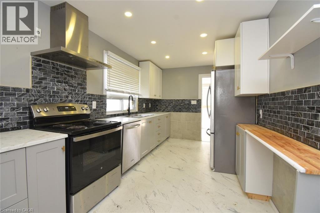 Kitchen featuring appliances with stainless steel finishes, island range hood, tasteful backsplash, recessed lighting, and white cabinetry - 371 Fairfield Avenue, Hamilton, ON - Indoor Photo Showing Kitchen