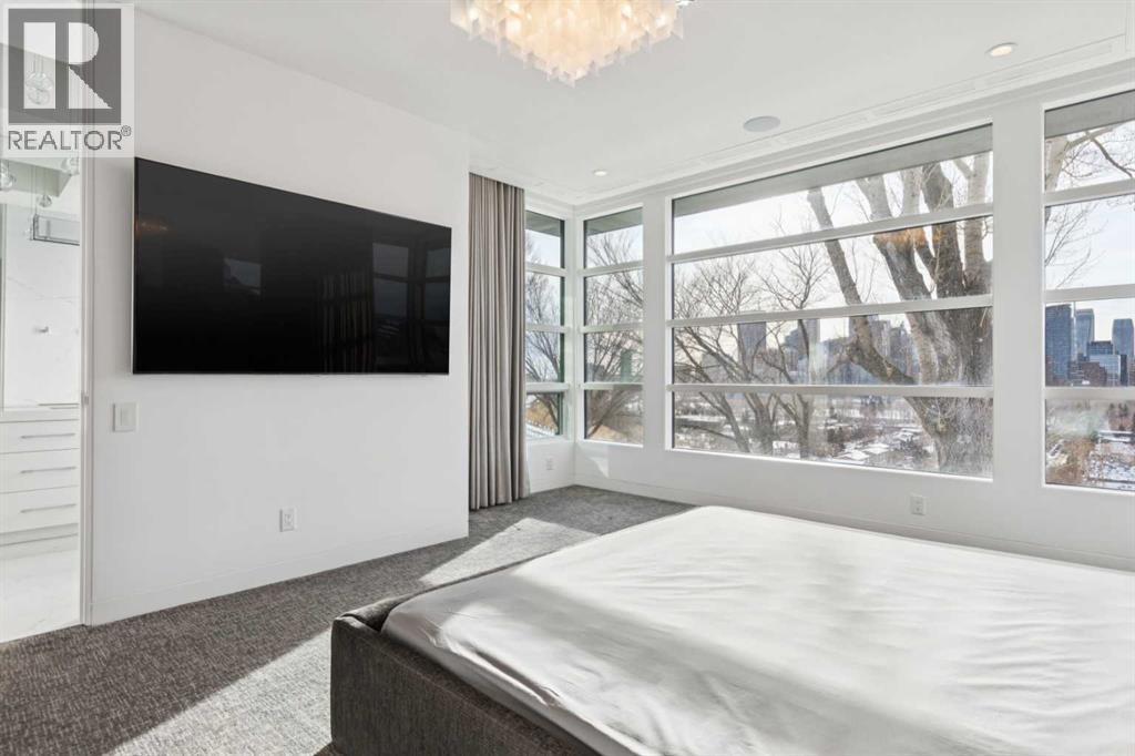 CORNER WINDOWS EXTEND THE VIEWS. WALL-MOUNTED TV - 530 Crescent Road Nw, Calgary, AB - Indoor Photo Showing Bedroom