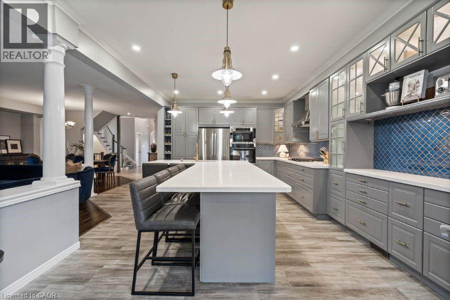 Kitchen with glass insert cabinets, gray cabinets, a kitchen breakfast bar, a center island, and tasteful backsplash - 151 Fair Street, Ancaster, ON