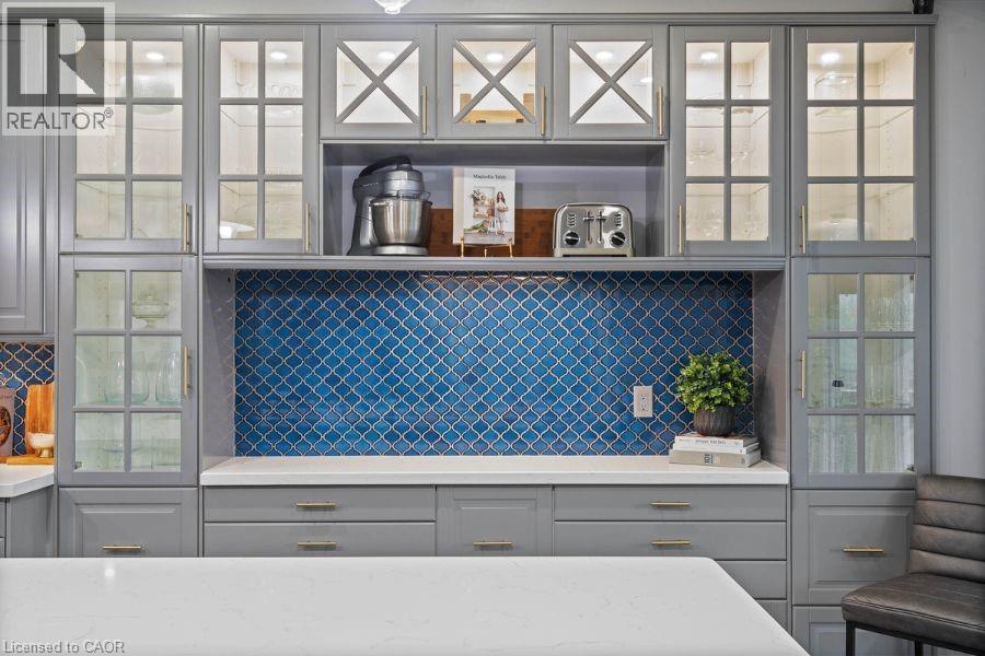 Bar area with gray cabinetry, glass insert cabinets, light stone counters, and backsplash - 151 Fair Street, Ancaster, ON