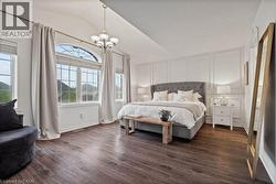 Bedroom featuring lofted ceiling, dark wood-style flooring, a chandelier, and a decorative wall -