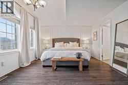 Bedroom with dark wood-style floors, a decorative wall, and a chandelier -