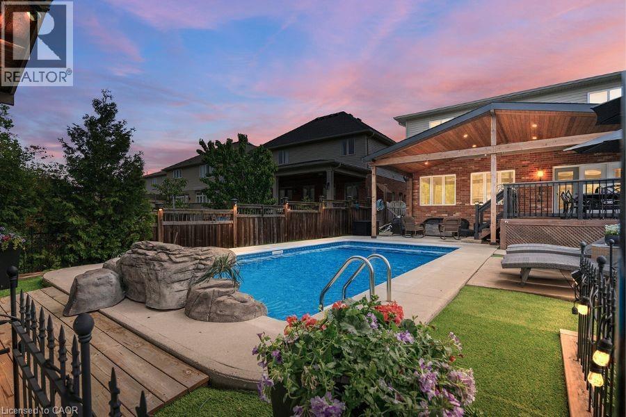 Pool at dusk featuring a patio area, a fenced backyard, an outdoor hangout area, and a wooden deck - 151 Fair Street, Ancaster, ON