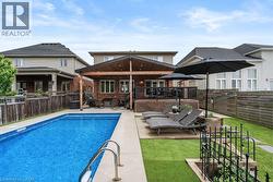 Back of house featuring a fenced backyard, a patio, an outdoor living space, and brick siding -
