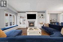 Living area with dark wood finished floors, a warm lit fireplace, recessed lighting, and built in shelves -