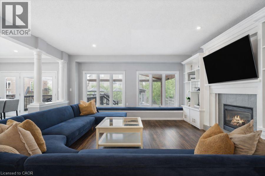 Living room with dark wood finished floors, a fireplace, ornate columns, and recessed lighting - 151 Fair Street, Ancaster, ON