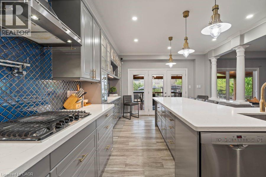Kitchen with appliances with stainless steel finishes, under cabinet range hood, gray cabinetry, french doors, and healthy amount of natural light - 151 Fair Street, Ancaster, ON