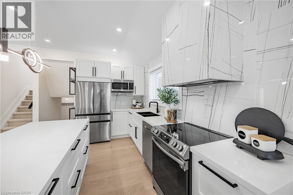 Kitchen featuring appliances with stainless steel finishes, light stone counters, white cabinetry, tasteful backsplash, and vaulted ceiling - 248 Wales Crescent, Oakville, ON - Indoor Photo Showing Kitchen With Double Sink With Upgraded Kitchen