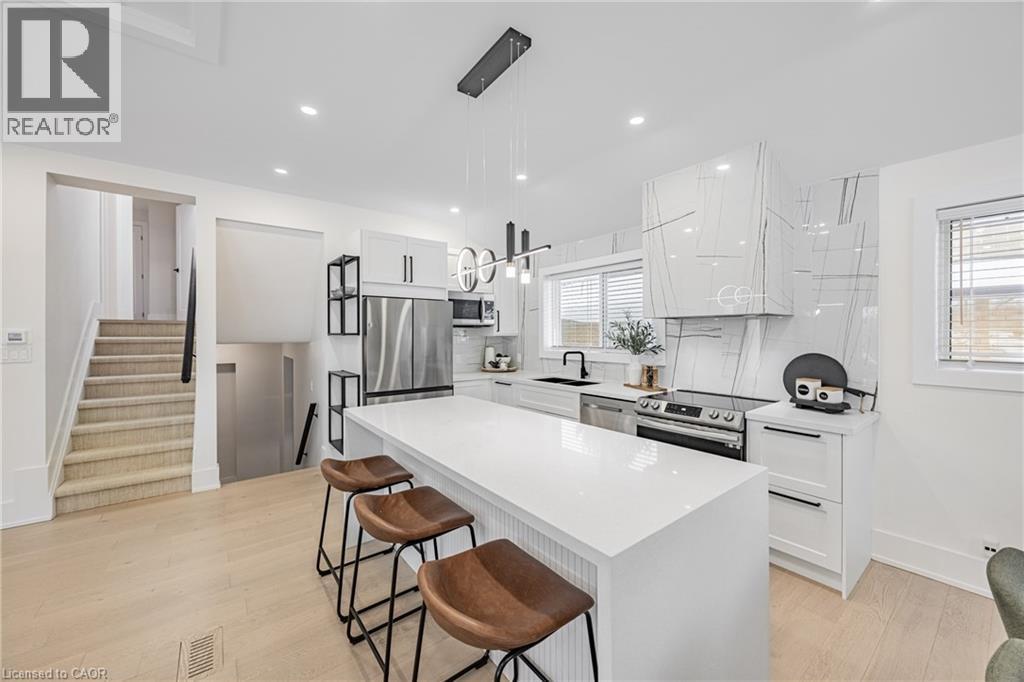 Kitchen with a breakfast bar, white cabinets, stainless steel appliances, pendant lighting, and light wood finished floors - 248 Wales Crescent, Oakville, ON - Indoor Photo Showing Kitchen With Upgraded Kitchen