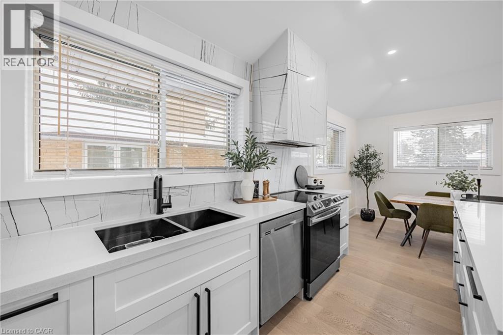 Kitchen with white cabinetry, appliances with stainless steel finishes, light wood finished floors, light stone countertops, and recessed lighting - 248 Wales Crescent, Oakville, ON - Indoor Photo Showing Kitchen With Double Sink