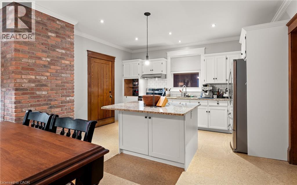 Kitchen with white cabinets, light stone countertops, hanging light fixtures, tasteful backsplash, and ornamental molding - 58 Hohner Avenue, Kitchener, ON - Indoor