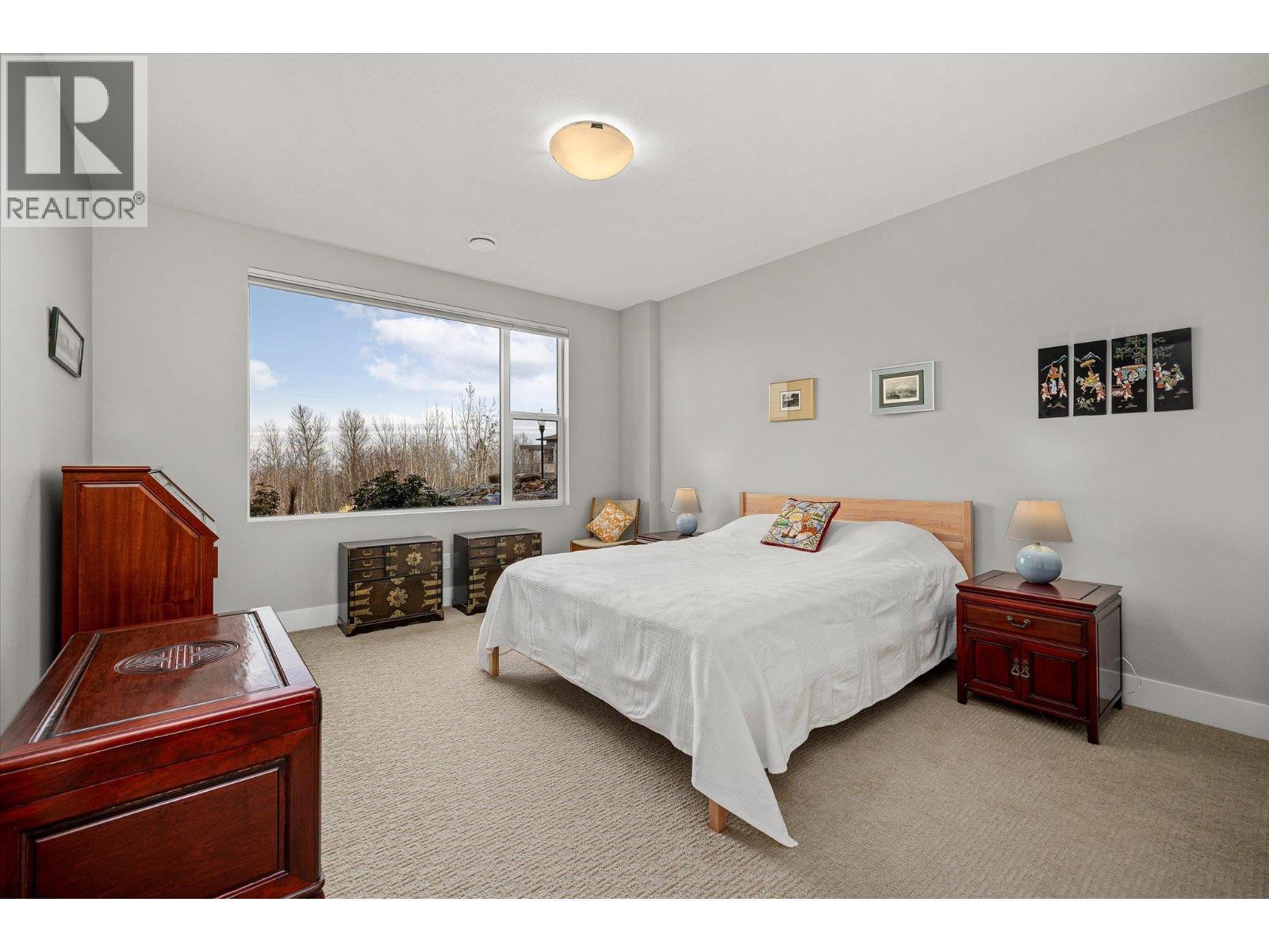 King-size 2nd bedroom with lake views and plush carpet - 468 Sparrow Hawk Court, Kelowna, BC - Indoor Photo Showing Bedroom